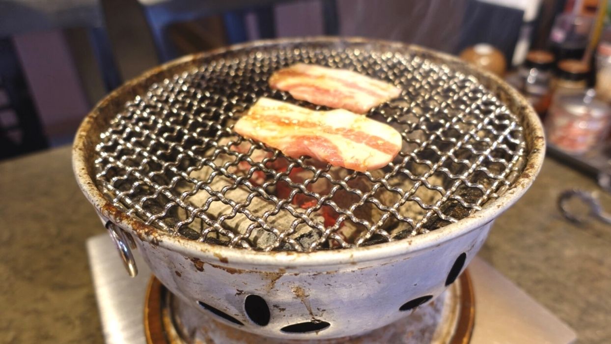 使い込まれた炭火焼肉コンロで豚カルビを焼きますよ〜。